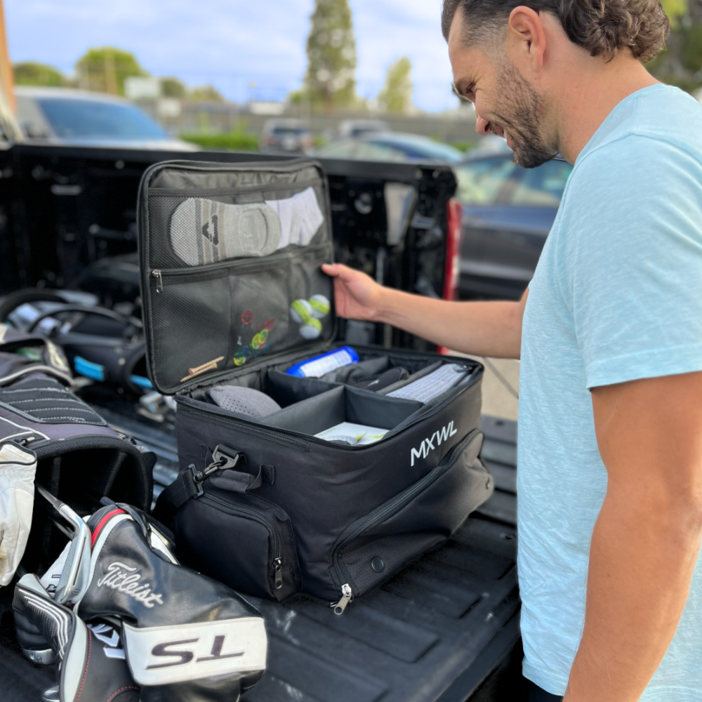 Man organizing golf equipment in a black bag on a truck bed